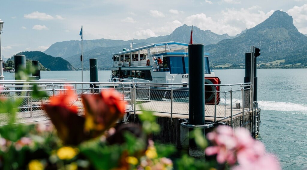 Wolfgangsee Boat Service (c) SalzburgerLand Tourismus Skyline Medien A boat moored at a lakeside jetty with mountains in the background and flowers in the foreground. (Enlarged view)