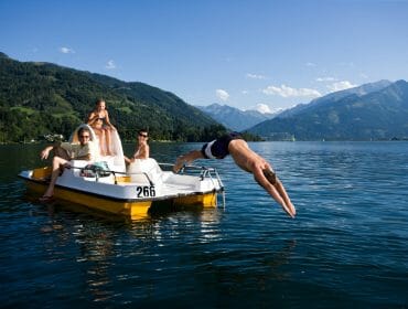Familie am gelben Tretboot - Kind köpfelt ins Wasser
