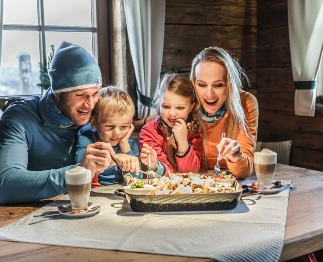 hochkönig-winter-familie Familie genießt Kaiserschmarrn in der Skihütte.