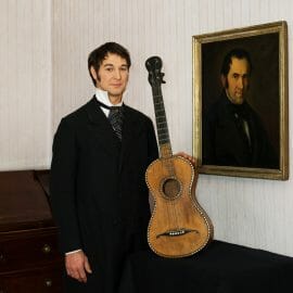 Franz Gruber standing holding his Guitar and posing for the camera