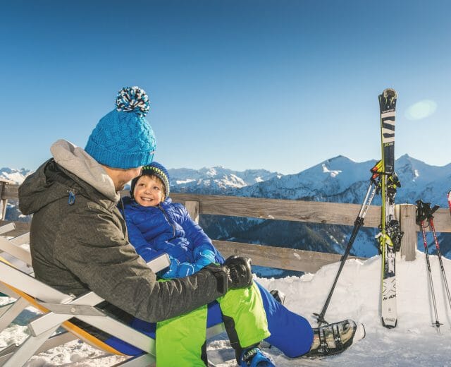 a man and a boy on top of a snow mountain with skis