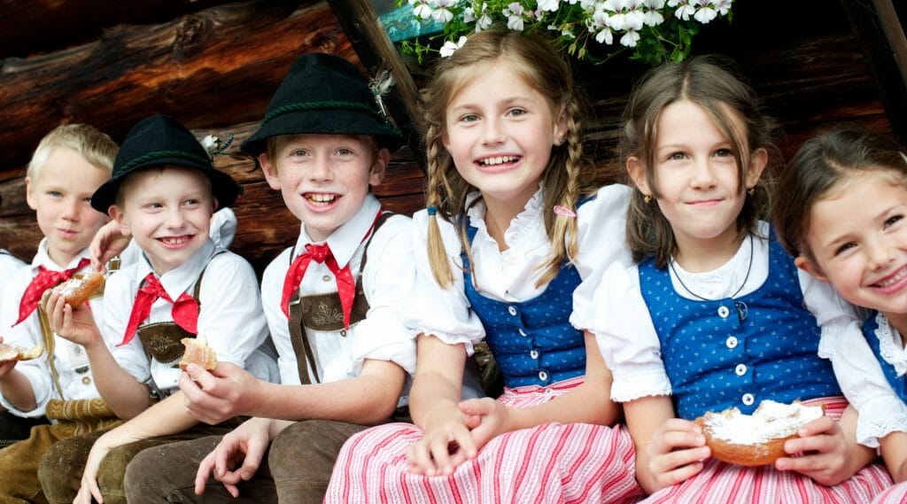 a group of children wearing costumes and sitting on a bench posing for the camera