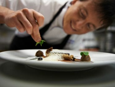 via-culinaria-dekoration a chief preparing a plate of food
