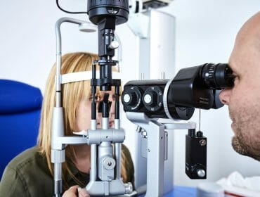 a man observing a lady eyes through an eye telescope
