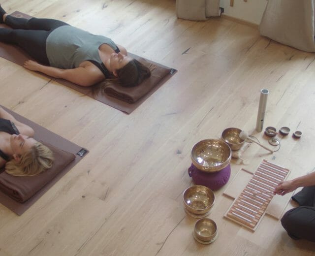 Das Alpenhaus Gasteinertal_Qi-Gong session Two people laying on the floor listening to an acoustic performance of Qi gong