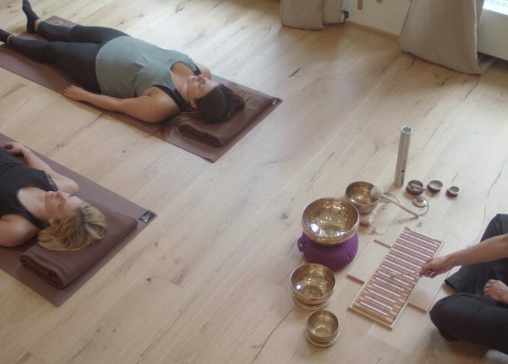 Two people laying on the floor listening to an acoustic performance of Qi gong