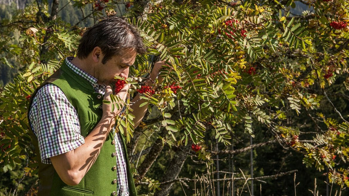 a man standing next to a tree sniffing a flower