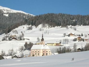  a snow covered mountain and lots of cottages covered in snow