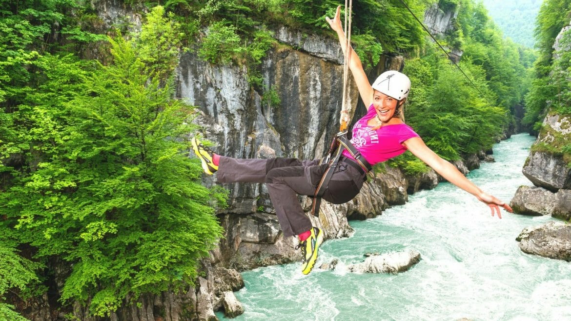 a lady climbing a cliff next to a waterfall