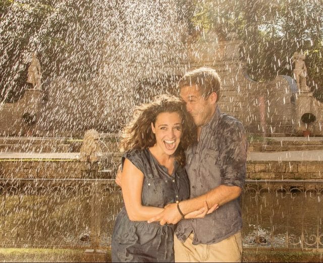 a couple standing in front of a fountain