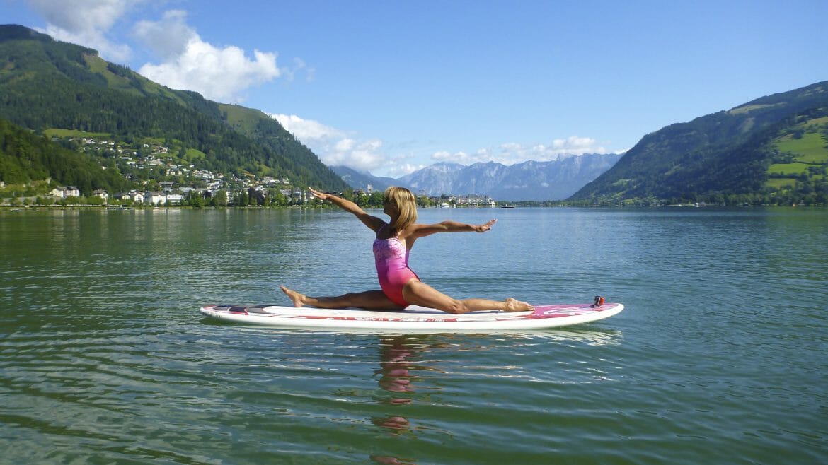 yoga on a surf board in a lake with a mountain in the background