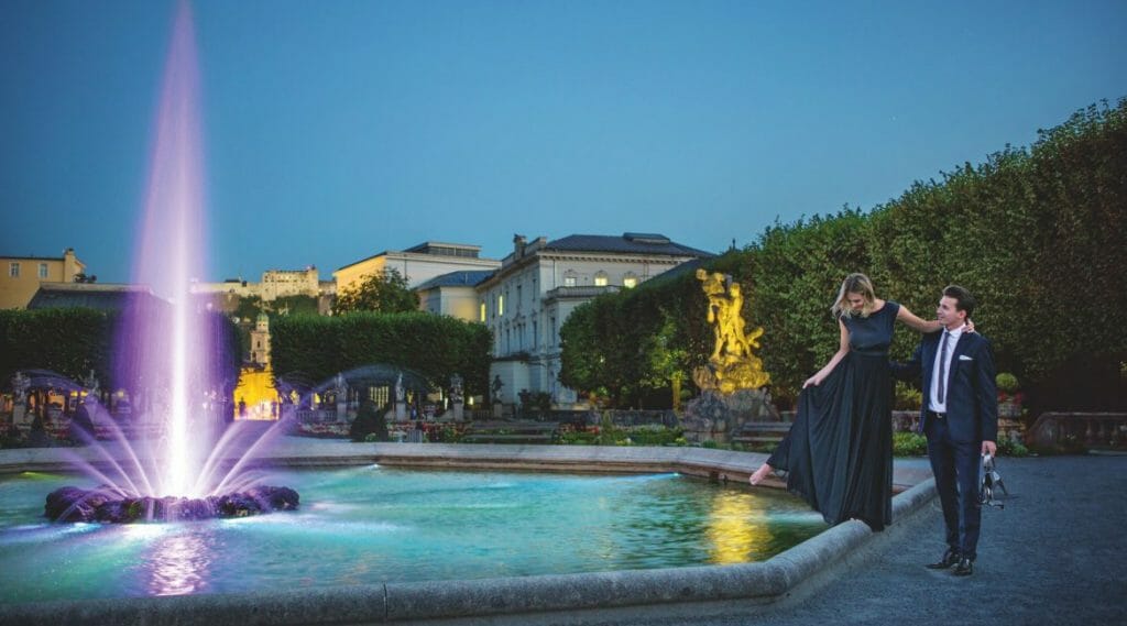 a couple standing in front of a fountain of water