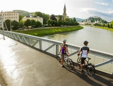 a couple standing next to the bicycles on a bridge