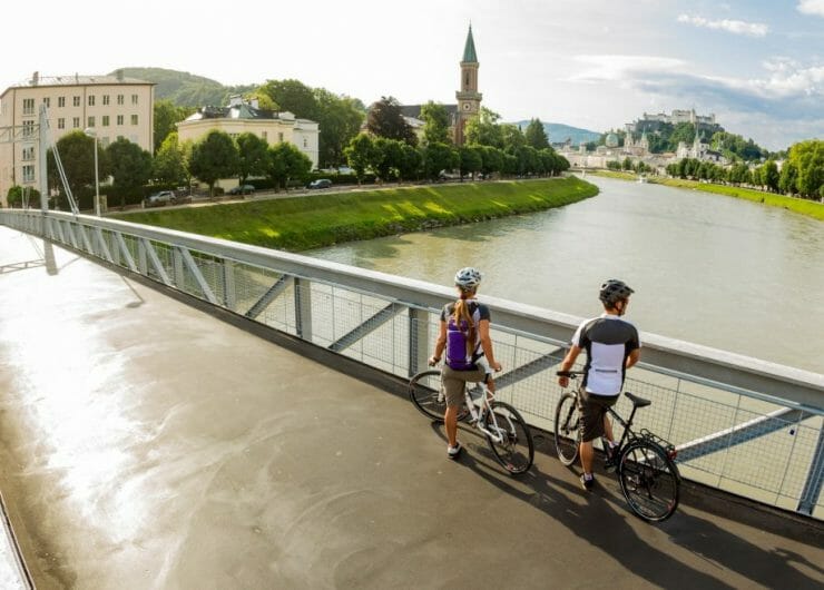 a couple standing next to the bicycles on a bridge