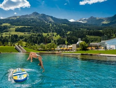 seen_jump a lady jumping in the water with a mountain in the background