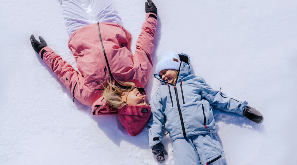 Chillout Mother-Daughter Ski Day © SalzburgerLand Tourismus, Lisa Eiersebner Adult and child in winter clothes lying on snow, looking at each other and smiling. (Enlarged view)