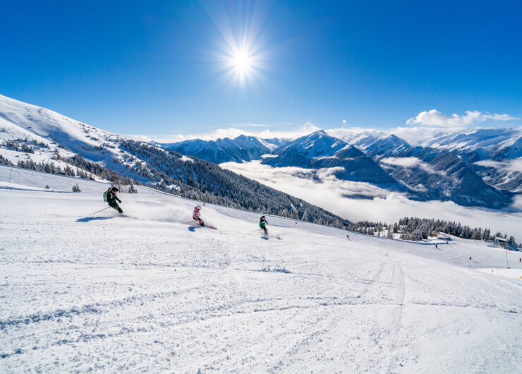 Wildkogelarena Winter Three skiers on perfect pists - mountains ind the background on a very sunny day