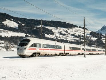 (c) Deutsche Bahn A white high-speed train travels through a snowy landscape with mountains in the background.