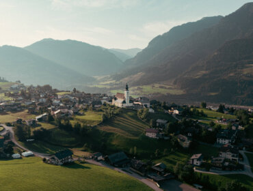 St.Veit in the Salzburger Sonnenterrasse Aerial view of the village St.Veit im Pongau with a church in the centre, surrounded by green hills and distant mountains.