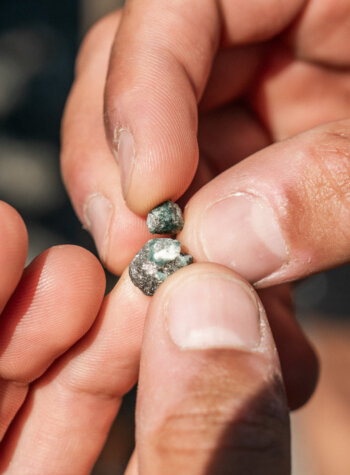 Fingers hold and break apart a rough, greenish mineral—discover more with SmartGuide audio guide SalzburgerLand.