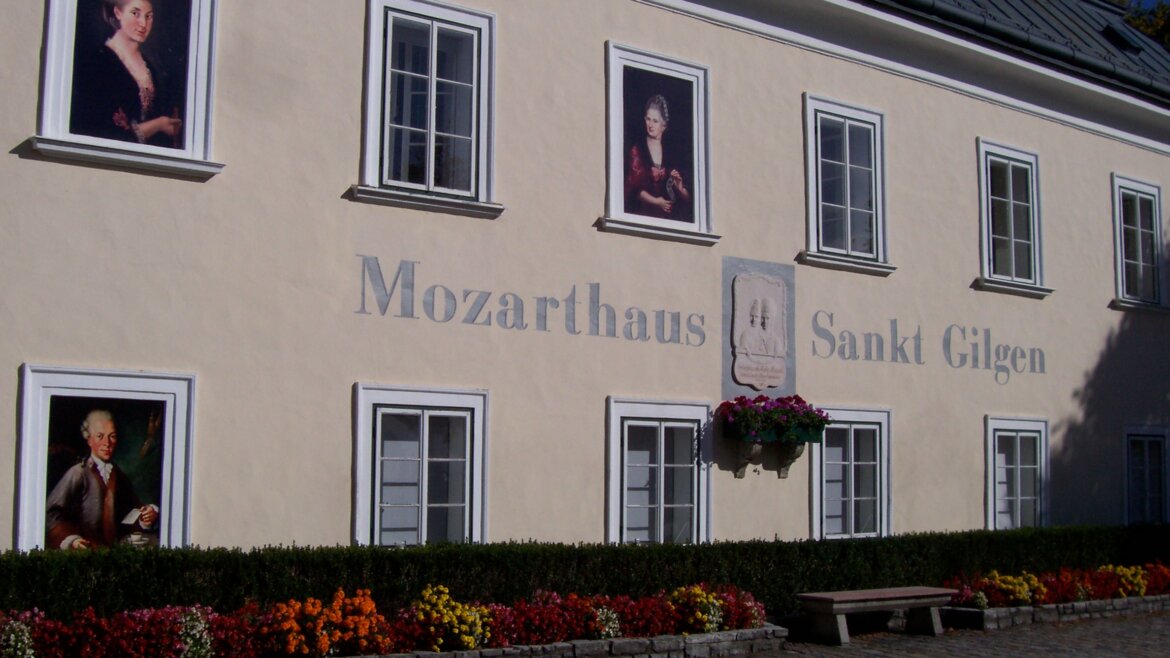 Mozarthaus in St. Gilgen am Wolfgangsee (c) Wolfgangsee_Tourismus Exterior of Mozarthaus Sankt Gilgen along the Mozart-Radweg, with portraits, windows, and colourful flowers. (Enlarged view)