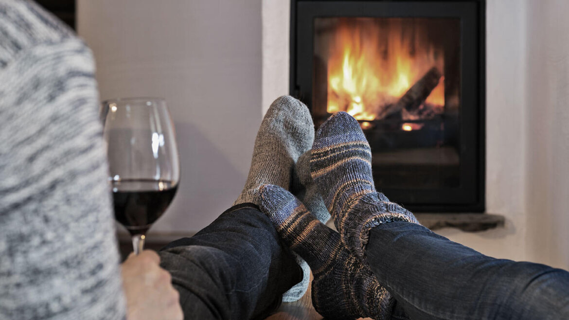 A couple's legs wearing thick socks in front of a fireplace