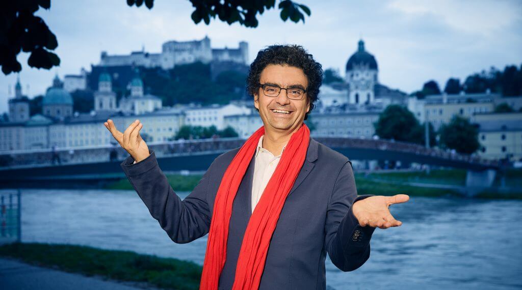 Rolando Villazon with red scarf, in the backround the city of Salzburg