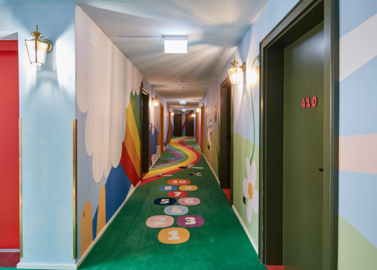 Colourful corridor with a hopscotch game on the floor and playful, nature-themed wall murals.