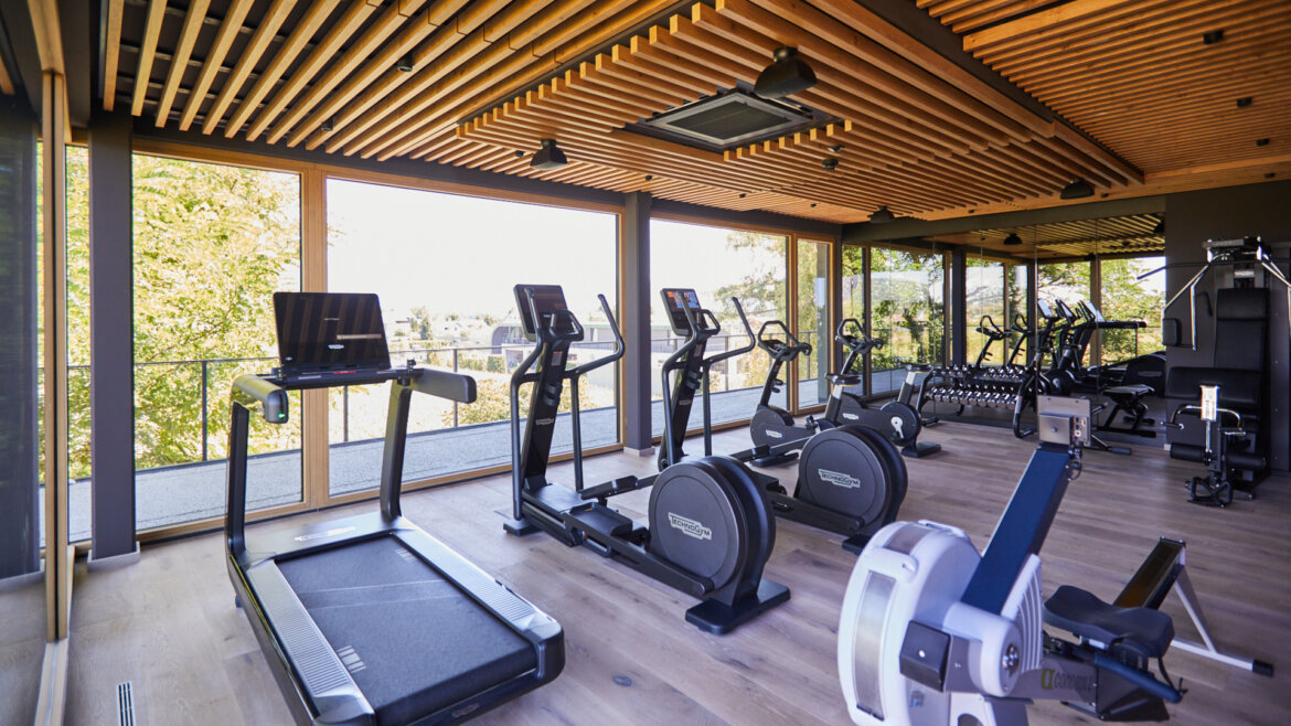Modern gym with treadmills, exercise bikes, and large windows letting in natural light. (Enlarged view)