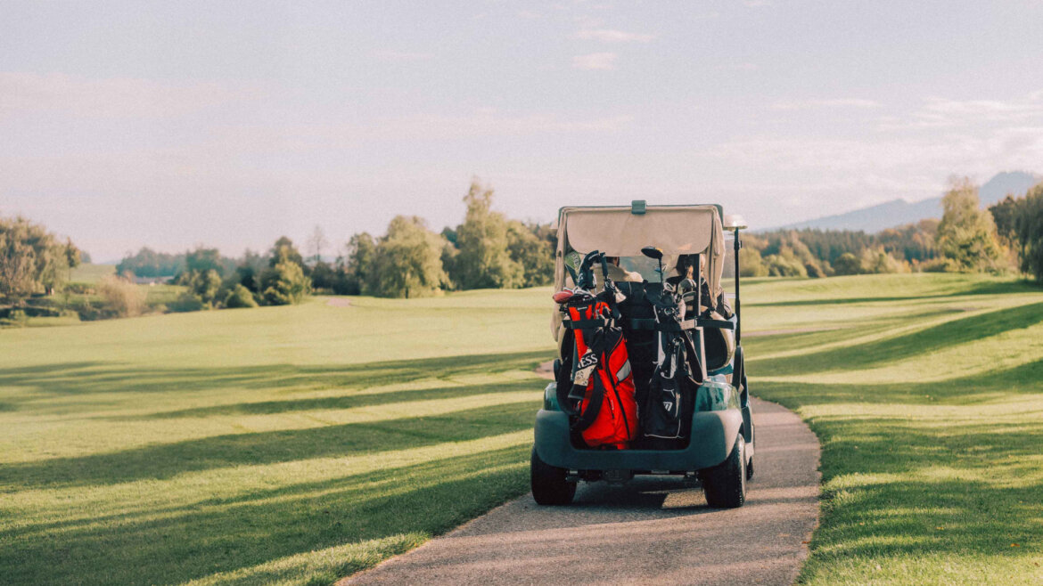 Elixhauser Wirt © Richard Schabetsberger A golf buggy with clubs on a path, surrounded by green grass and trees on a sunny day. (Enlarged view)