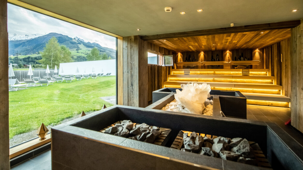 © TAUERN SPA Zell am See-Kaprun Modern sauna with wooden interior, large salt crystal, and a scenic mountain view through glass window. (Enlarged view)