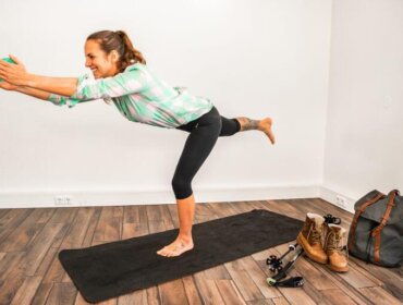 Hiking fitness exercise (c) Maria Pirchner Woman balancing on one leg on a yoga mat indoors, with hiking kit and boots nearby on the floor.