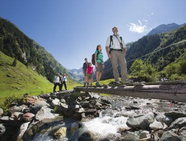 A nemzeti park természetvédelmi őre keresztül vezeti a túrázó családot egy fa hídon