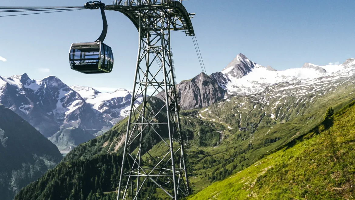 A felvonó a zöldellő hegyoldalon emelkedik Zell am See-ben, a háttérben hófödte hegycsúcsok.