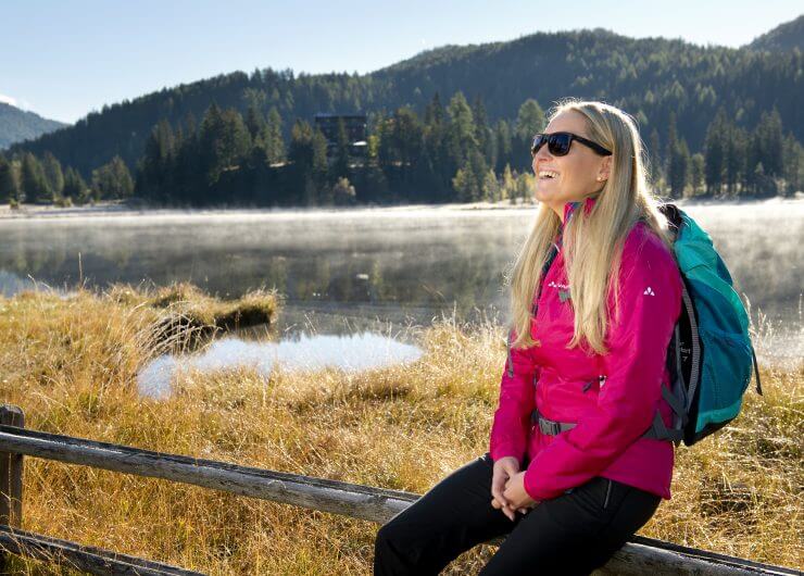 Szőke napszemüveges turista hölgy ül a Tamsweg mellett fekvő Prebersee tónál