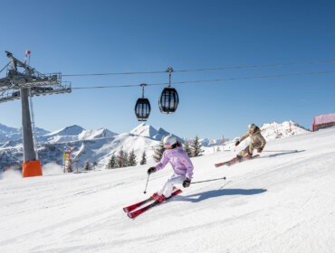 Grossarltal Skifahren_64_© LorenzMasser Két síelő ereszkedik le egy havas lejtőn a Grossarltalban felvonó alatt az osztrák hegyekben.