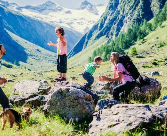 Vidáman túrázó család az alpesi hegyek között.