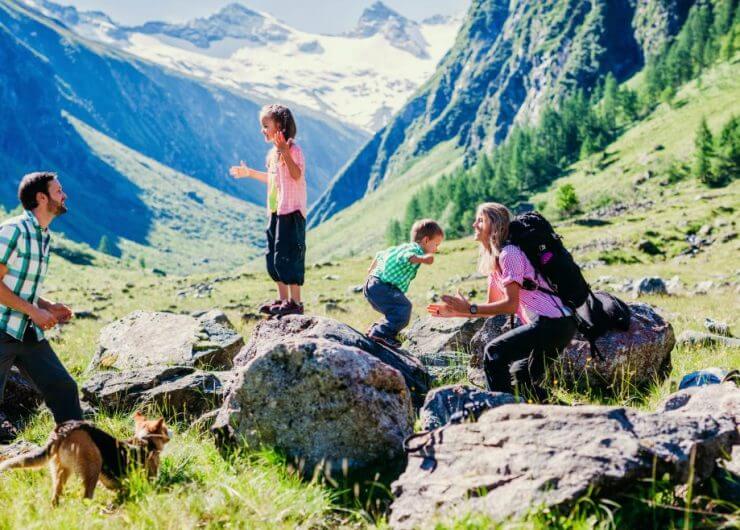 Vidáman túrázó család az alpesi hegyek között.