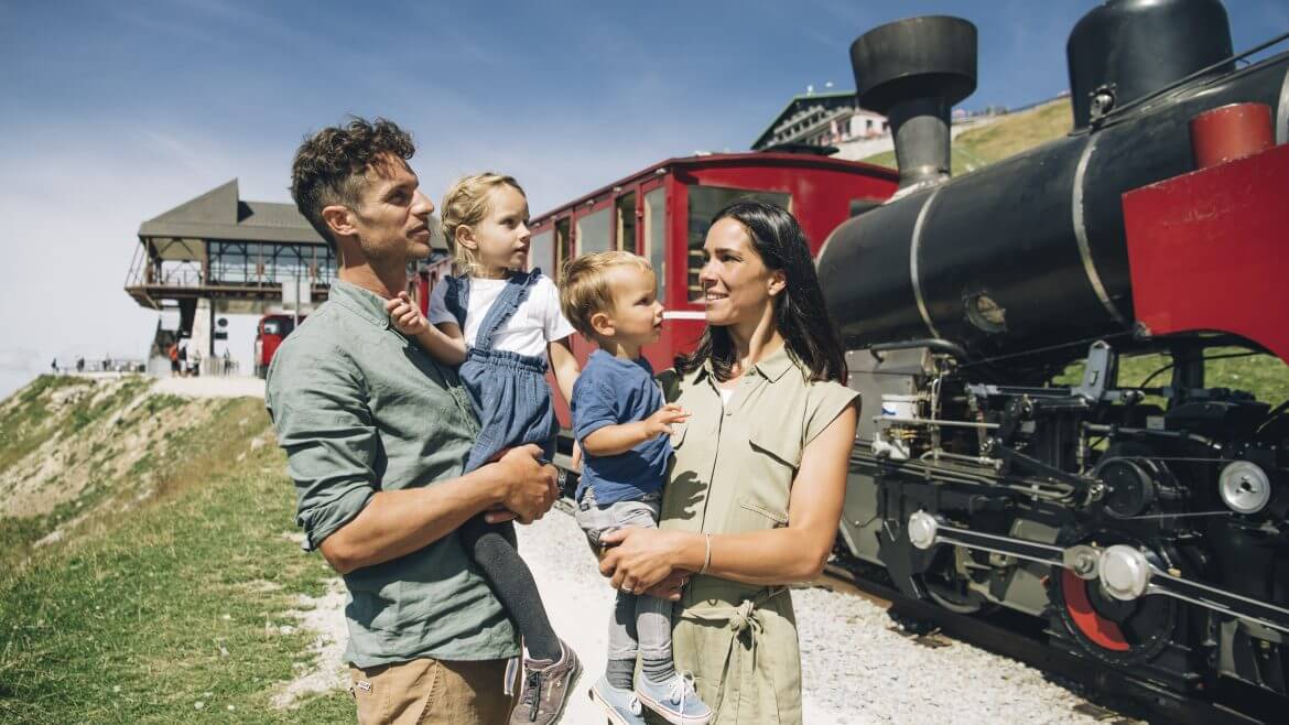 Kiránduló család áll a Schafbergbahn hegyi megállójánál