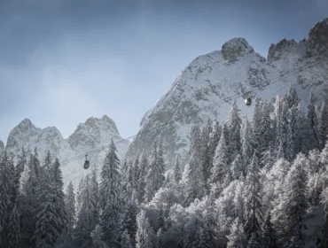 Télen a felvonók a hóval borított fák felett haladnak a Dachstein West szaggatott, hófedte hegyei felé.