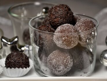 Rum-Lebkuchen-Kugeln Csokoládé trüffelekkel töltött pohár, némelyiket szórócukorral, másokat cukorral bevonva, ezüst díszek mellett.