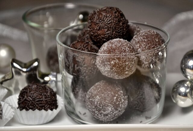 Rum-Lebkuchen-Kugeln Csokoládé trüffelekkel töltött pohár, némelyiket szórócukorral, másokat cukorral bevonva, ezüst díszek mellett.