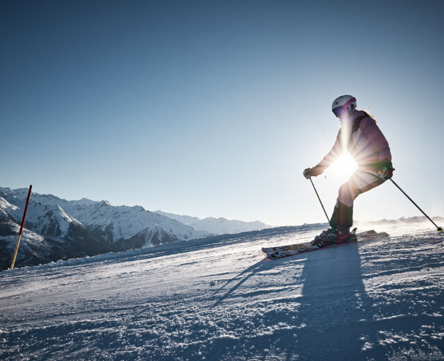 Skifahren in Mittersill_c-Michael Hochfellner_Mittersillplus_277 (2) Egy síelő az osztrák Alpokban, a ragyogó napfényben szeli át a havas hegyoldalt.