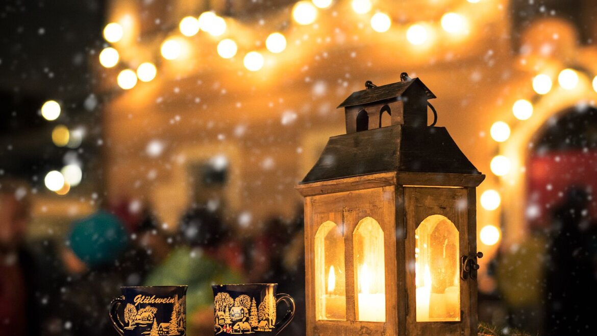 Lanterna accesa e due tazze festose su un tavolo con luci sfocate del Tennengau e neve leggera sullo sfondo. (Vista ingrandita)