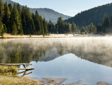 Veduta mistica del Prebersee nel Lungau con nebbia bassa e paesaggio protetto del Parco della Biosfera