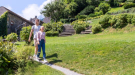 Una coppia passeggia mano nella mano su un sentiero erboso, godendosi un giardino illuminato dal sole con la SalzburgerLand Card.