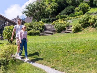 Una coppia passeggia mano nella mano su un sentiero erboso, godendosi un giardino illuminato dal sole con la SalzburgerLand Card.