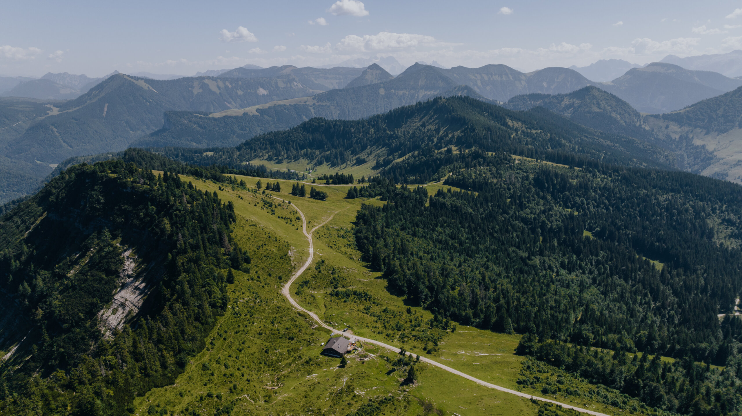Wandern im Tennengau-Spielbergalm in Krispl-Gaissau; ©creatingclick Un sentiero tortuoso conduce a una piccola casa su un verde crinale del Tennengau, circondata da boschi e cime.