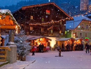 Mercatino di Natale in piazza a Grossarl mentre nevica