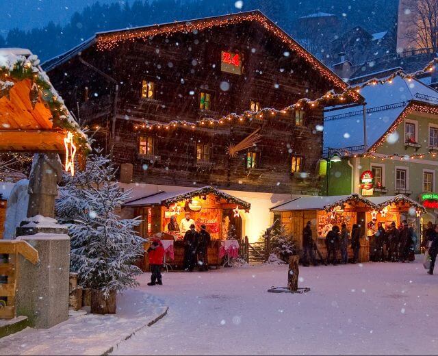 Mercatino di Natale in piazza a Grossarl mentre nevica